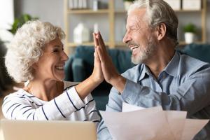 An elderly woman and man high fiving in a living room