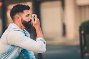 Man using an inhaler for asthma symptoms