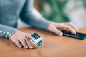 Woman checking her oxygen levels and sending results to her provider remotely