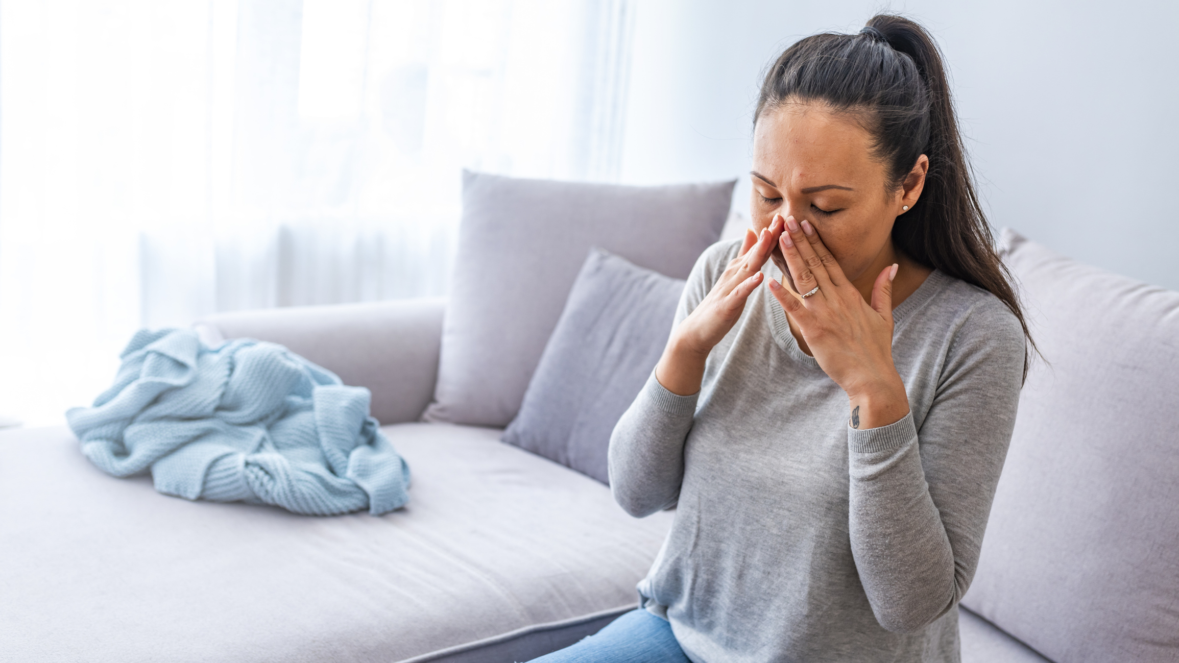 Woman gripping the sides of her nose after experiencing sinusitis symptoms