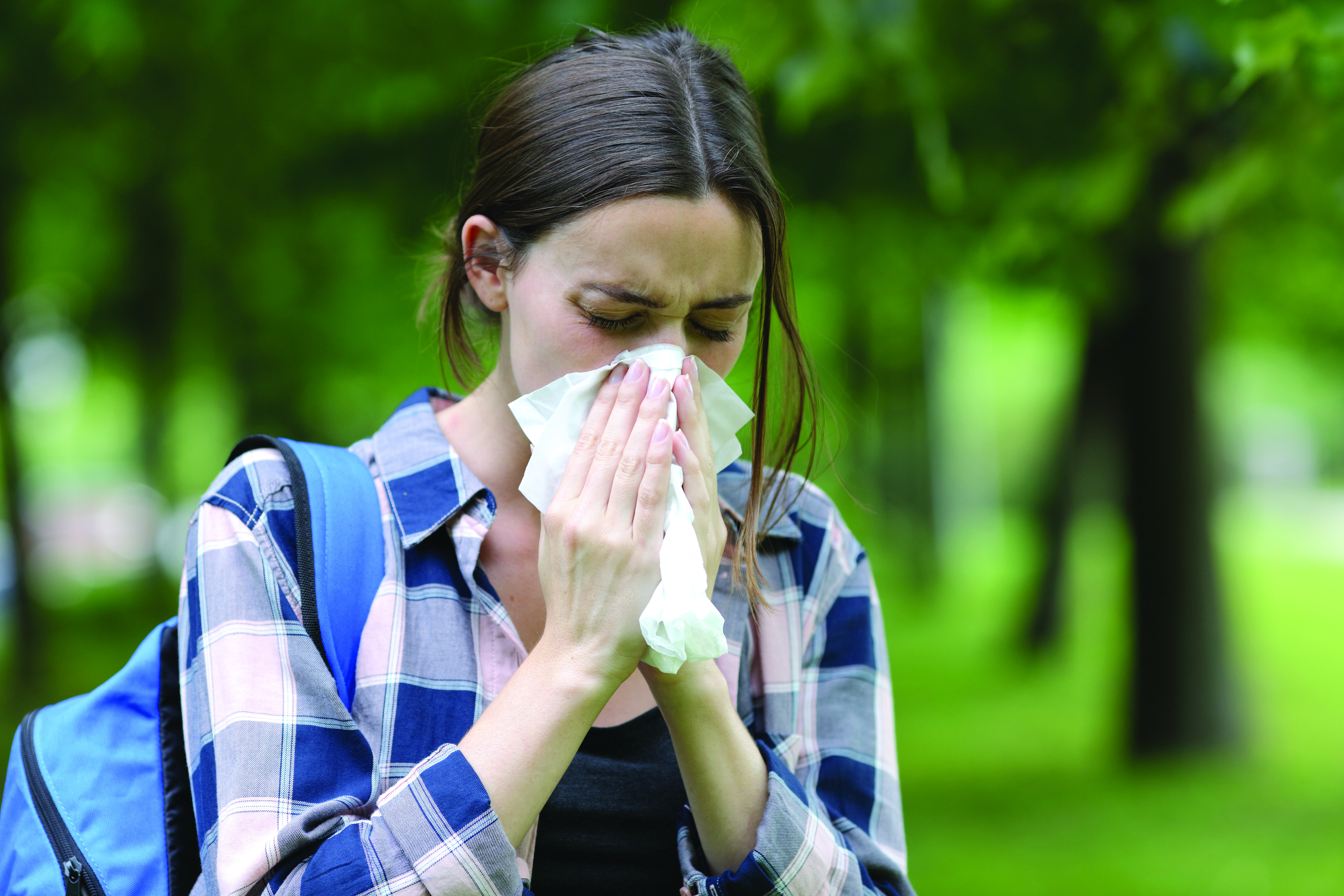 A person blowing their nose who suffers from chronic sinusitis.