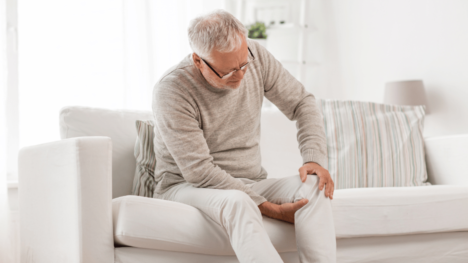 Man gripping his knee, experiencing joint pain in winter