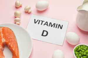 Vitamin D rich foods, including salmon, eggs, mushrooms, and milk, on a pink background